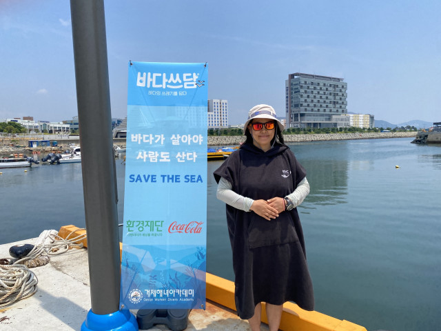 거제해녀아카데미 소속 활동가 박체은 씨가 수중 정화활동을 통해 깨끗해진 바다를 배경으로 기념사진을 촬영하고 있다(사진=환경재단)